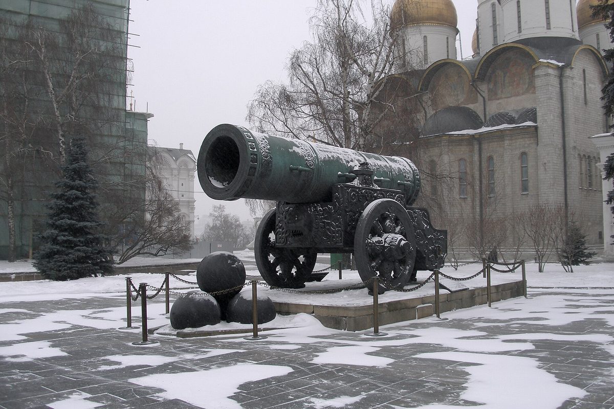 Царь-пушка на лафете с ядрами, вокруг снег, за ней стены собора