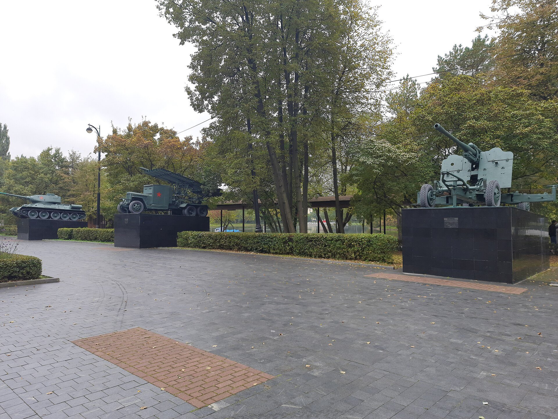 Танк Т-34, реактивная установка «Катюша» на грузовике и зенитная пушка на чёрных постаментах на Площади Мужества