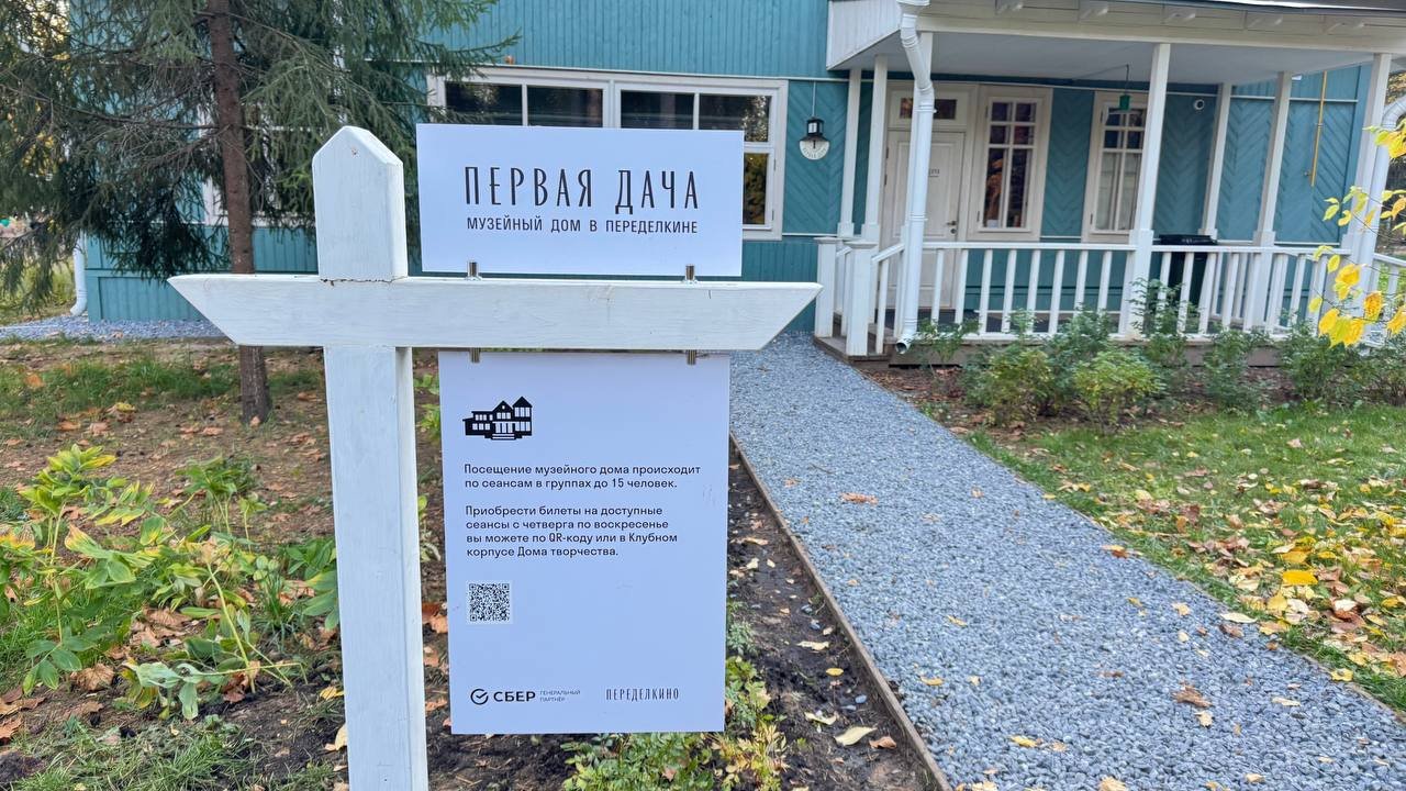 Белый деревянный указатель «Первая дача. Музейный дом в Переделкине» у бирюзового корпуса