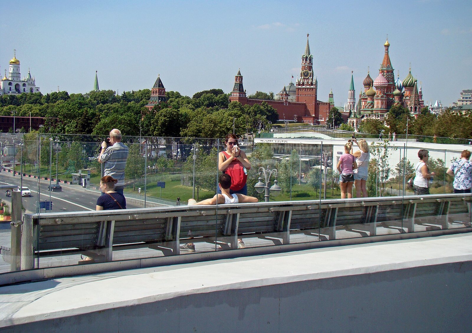 Люди на Парящем мосту в парке Зарядье фотографируют Кремль и собор Василия Блаженного