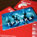 Голубая карта «Тройка» лежит на красных бумажных билетах «Единый» с логотипами метро и наземного транспорта